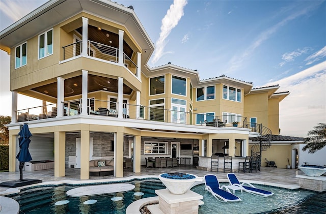 back of house featuring a swimming pool with hot tub, a balcony, and an outdoor bar