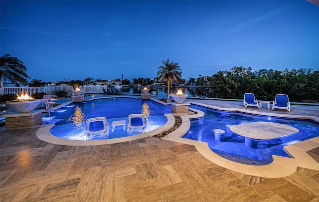 pool at dusk featuring pool water feature, an outdoor fire pit, a jacuzzi, and a patio area