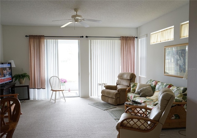 carpeted living room with ceiling fan and a textured ceiling