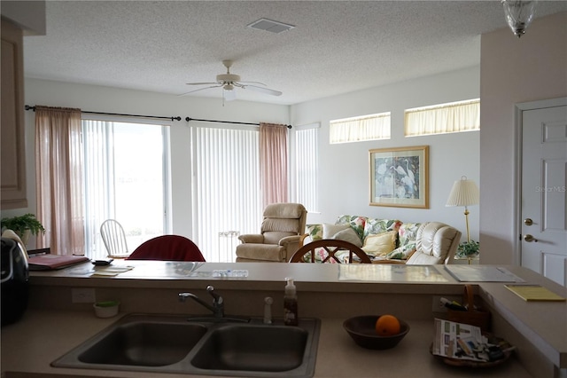 living room with ceiling fan, sink, and a textured ceiling