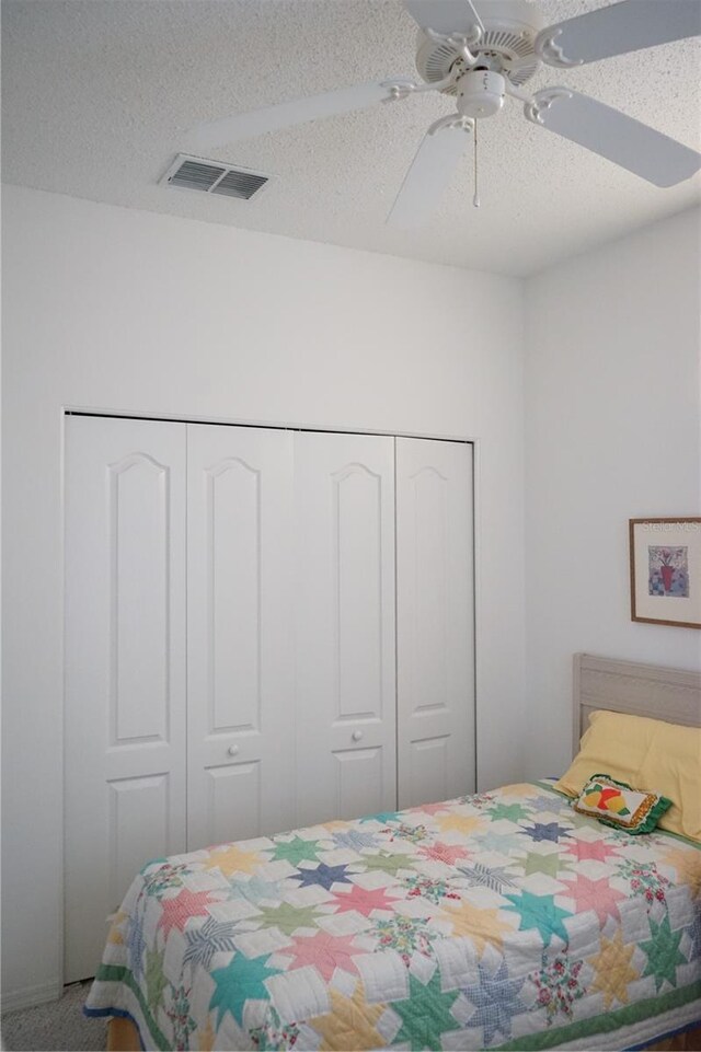 bedroom with a closet, ceiling fan, carpet floors, and a textured ceiling