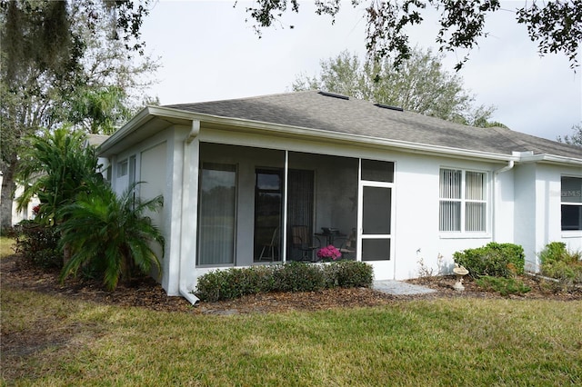 view of side of property featuring a lawn and a sunroom