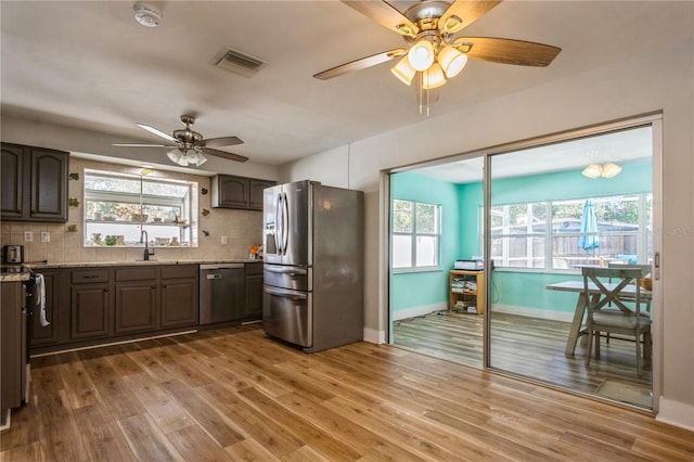 kitchen with hardwood / wood-style flooring, tasteful backsplash, appliances with stainless steel finishes, and dark brown cabinets