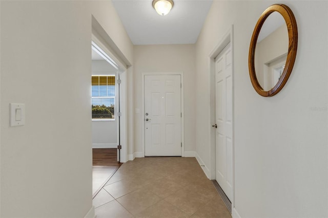 doorway featuring baseboards and light tile patterned floors