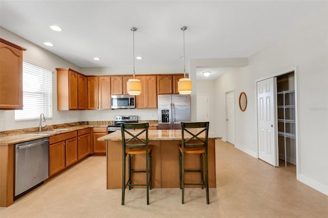 kitchen featuring a kitchen island, light stone counters, stainless steel appliances, a kitchen bar, and a sink