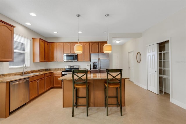 kitchen featuring recessed lighting, appliances with stainless steel finishes, a sink, a kitchen island, and a kitchen bar