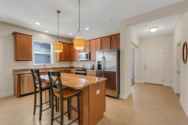 kitchen featuring light stone counters, recessed lighting, a kitchen breakfast bar, appliances with stainless steel finishes, and a center island