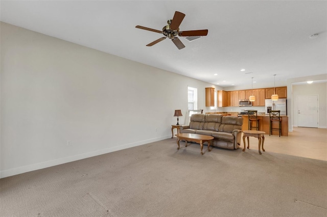 living area with a ceiling fan, recessed lighting, light carpet, and baseboards