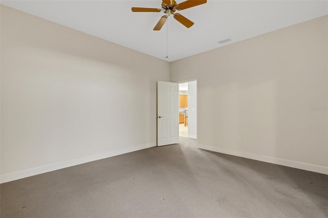 carpeted spare room featuring ceiling fan and baseboards