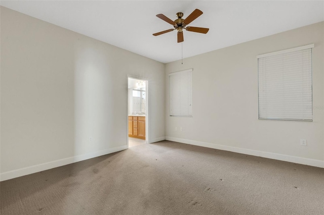 spare room with baseboards, ceiling fan, and light colored carpet