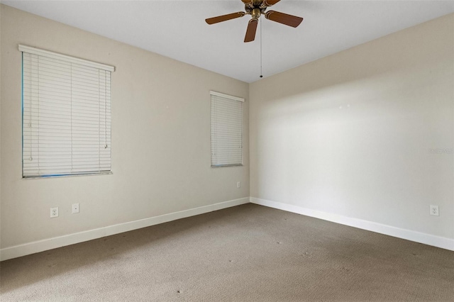 carpeted empty room featuring a ceiling fan and baseboards