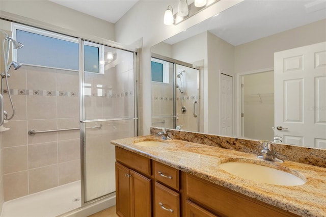 full bath featuring a stall shower, a healthy amount of sunlight, a sink, and double vanity