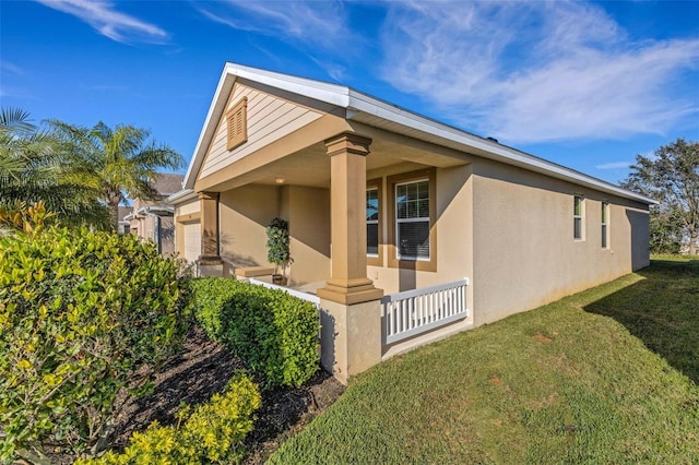 exterior space with stucco siding, covered porch, and a front yard