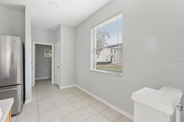 interior space featuring stainless steel fridge and light tile patterned floors