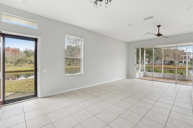 tiled empty room with plenty of natural light, ceiling fan, and a water view