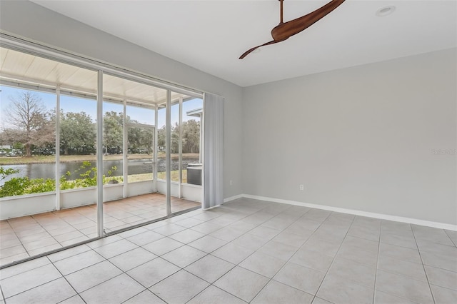 tiled empty room featuring a water view and ceiling fan