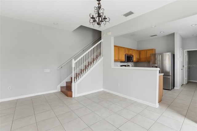 kitchen featuring light tile patterned floors, appliances with stainless steel finishes, an inviting chandelier, hanging light fixtures, and kitchen peninsula