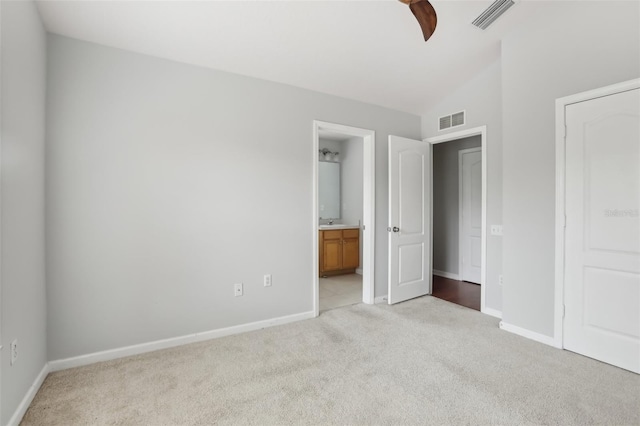 unfurnished bedroom with ensuite bathroom, vaulted ceiling, light colored carpet, and ceiling fan