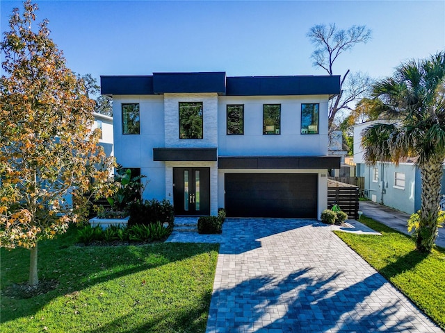 modern home featuring stucco siding, a front lawn, decorative driveway, french doors, and an attached garage