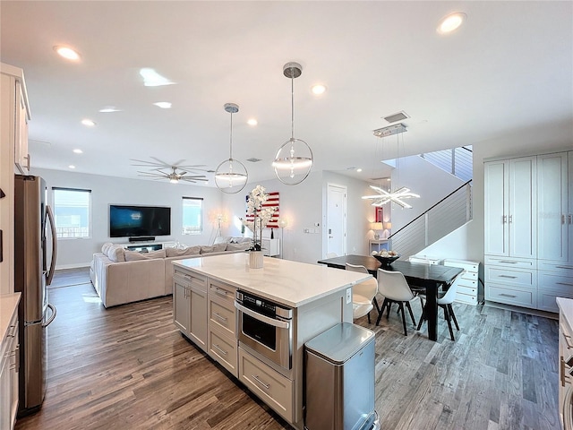 kitchen with decorative light fixtures, wood finished floors, open floor plan, recessed lighting, and stainless steel appliances