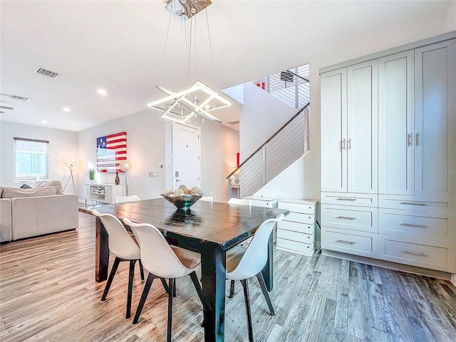 dining room with a notable chandelier, stairway, light wood-type flooring, and visible vents