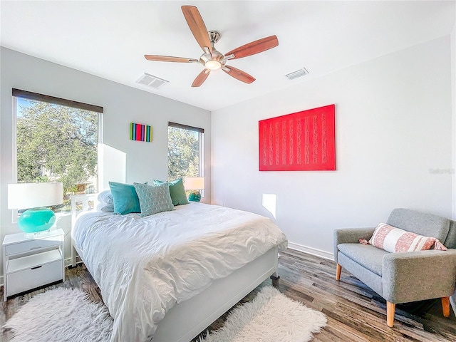 bedroom featuring ceiling fan, visible vents, baseboards, and wood finished floors