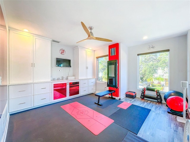 workout area with dark hardwood / wood-style flooring and ceiling fan