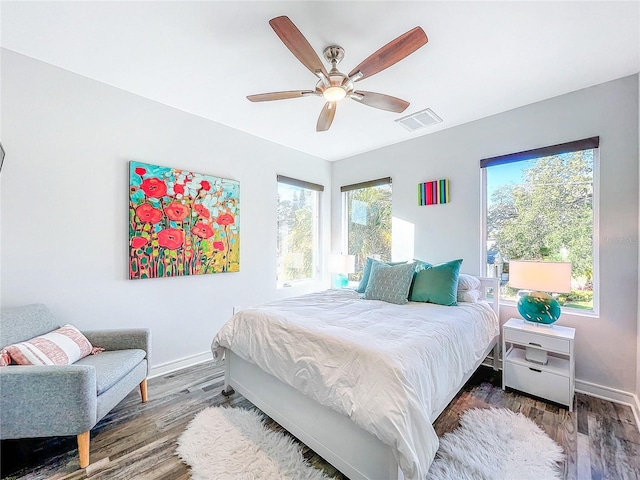 bedroom featuring ceiling fan, dark hardwood / wood-style floors, and multiple windows