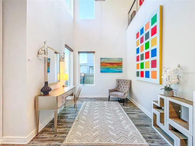 sitting room with hardwood / wood-style floors and a towering ceiling