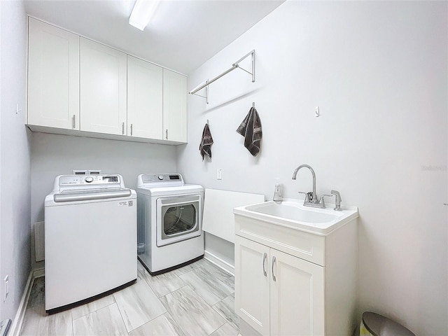 laundry area featuring separate washer and dryer, sink, and cabinets