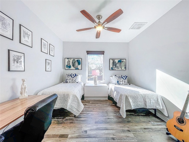 bedroom with ceiling fan, visible vents, and wood finished floors