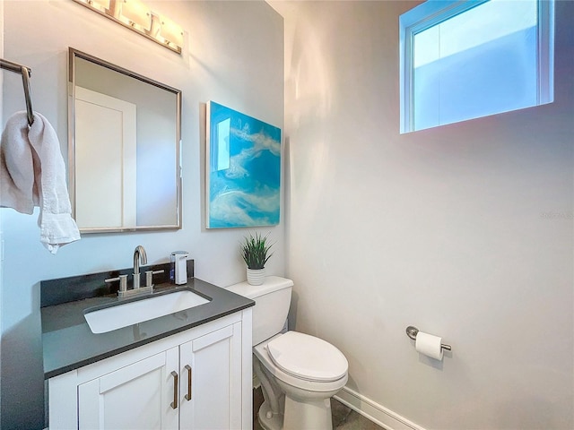 bathroom with vanity, toilet, and baseboards