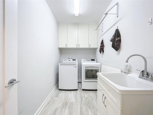 clothes washing area with cabinets, washing machine and dryer, and sink