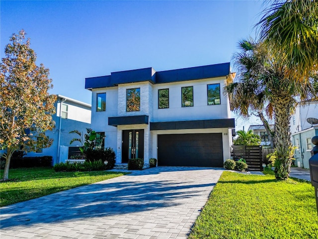 modern home with stucco siding, an attached garage, decorative driveway, and a front yard