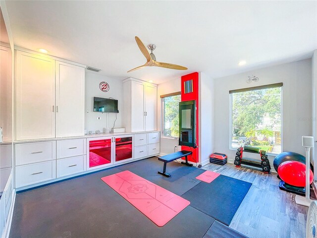 exercise room featuring dark wood-type flooring, a ceiling fan, visible vents, and baseboards