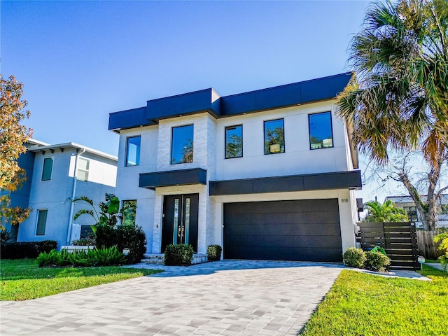 contemporary home featuring decorative driveway, a garage, and stucco siding