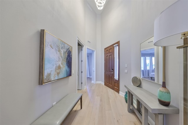 hall with light hardwood / wood-style floors and a high ceiling