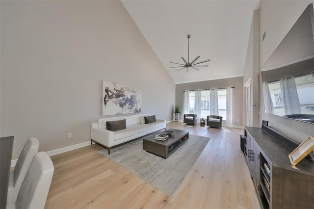 living room with ceiling fan, light hardwood / wood-style flooring, and a high ceiling