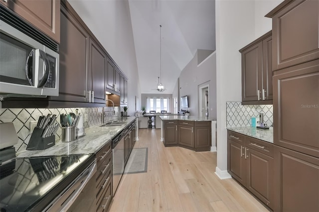 kitchen with pendant lighting, sink, dark brown cabinets, stainless steel appliances, and tasteful backsplash