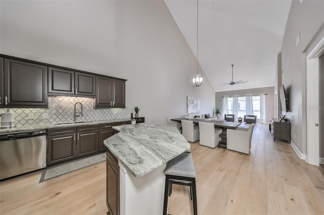 kitchen with sink, a breakfast bar, dishwasher, high vaulted ceiling, and tasteful backsplash