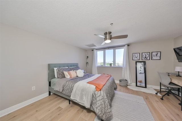 bedroom with ceiling fan, light hardwood / wood-style floors, and a textured ceiling