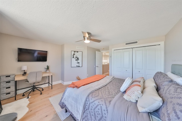 bedroom with ceiling fan, a textured ceiling, a closet, and light hardwood / wood-style flooring