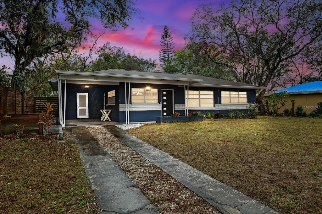 view of front of home with a carport and a yard