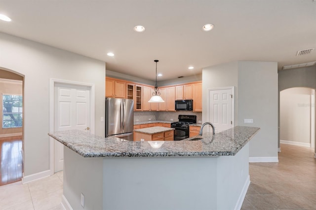 kitchen with a spacious island, black appliances, hanging light fixtures, light tile patterned floors, and backsplash