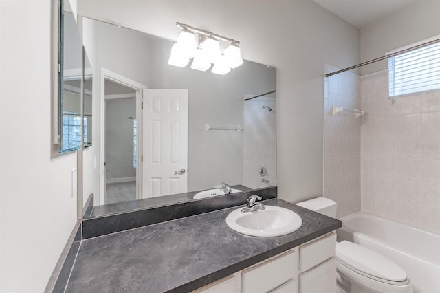 full bathroom featuring tiled shower / bath, vanity, and toilet