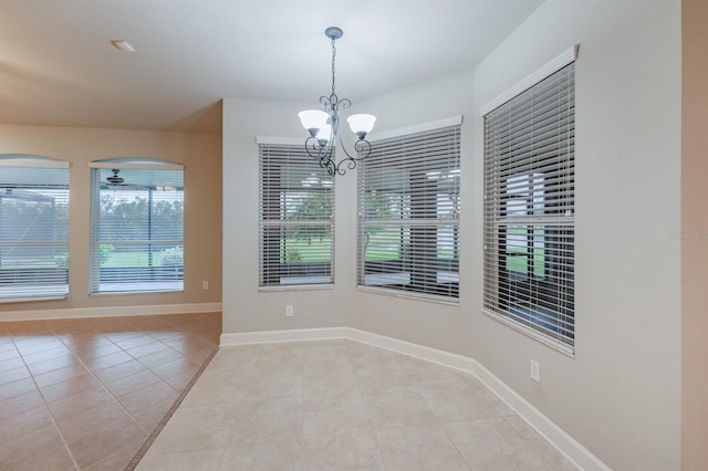 tiled empty room featuring a chandelier