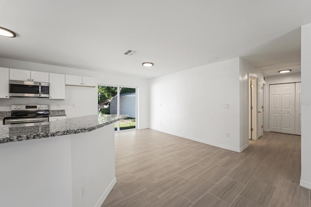 kitchen with white cabinetry, appliances with stainless steel finishes, and dark stone countertops