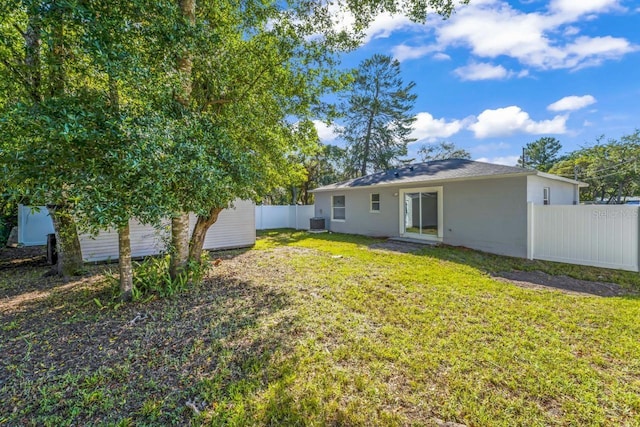 rear view of property with central AC and a lawn