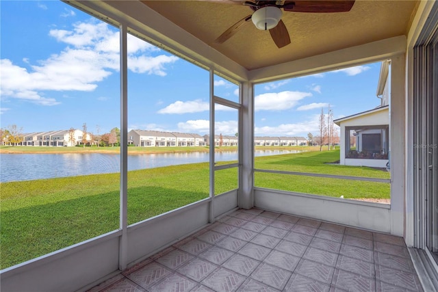 unfurnished sunroom with ceiling fan and a water view