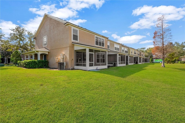 rear view of property with central AC, a sunroom, and a lawn